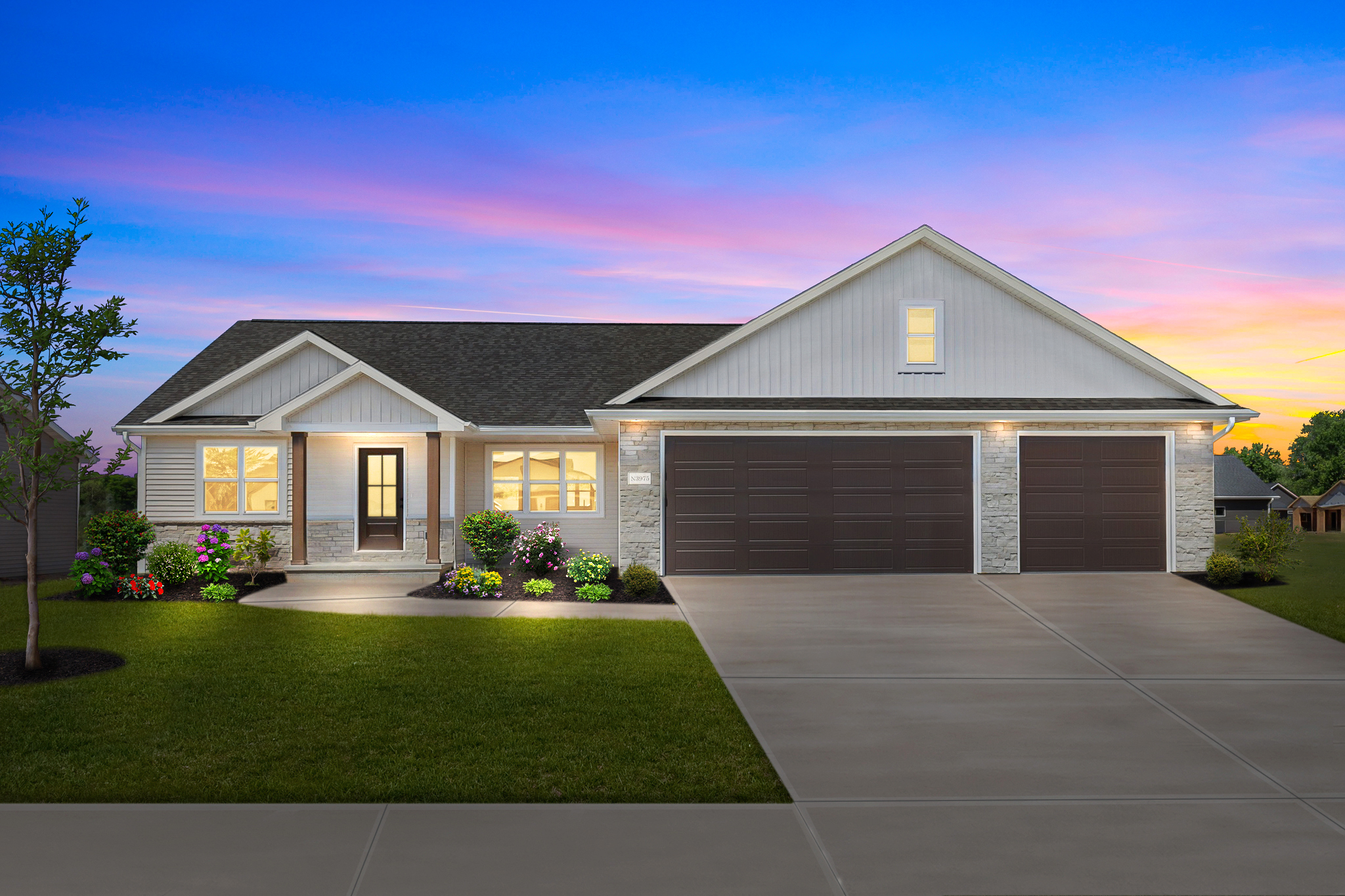 Riverwood ranch with a covered front porch, gray siding, and white garage doors