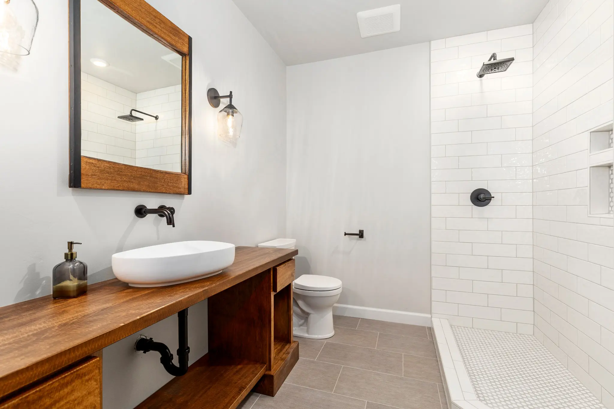 Riverwood bathroom with a wood vanity, vessel sink, and white subway-tile shower