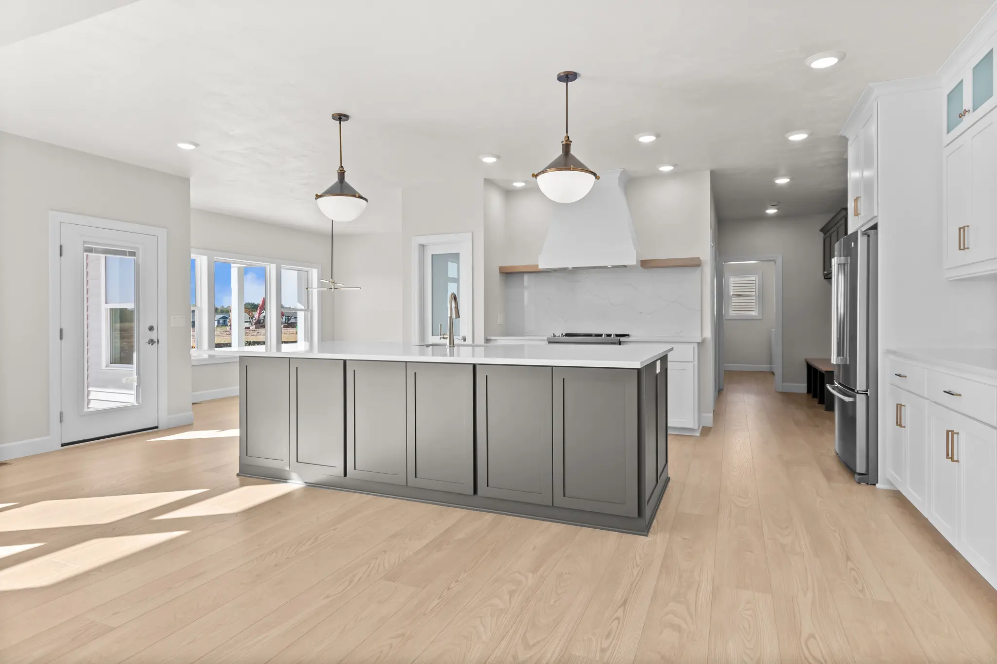 Riverwood kitchen with a large gray island, white cabinets, and light wood floors
